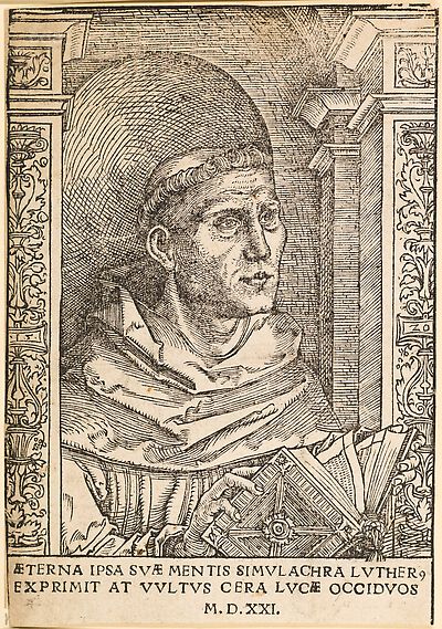 Martin Luther als Augustinermönch im Ordenshabit, Halbfigur nach rechts, mit Buch, vor einer halbrunden Nische, unter gestaffelten Bögen mit Kämpfergesimsen und Ornamentpilastern, mit Inschrift