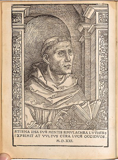 Martin Luther als Augustinermönch im Ordenshabit, Halbfigur nach rechts gewandt, mit Buch, vor einer halbrunden Nische, unter gestaffelten Rundbogen, mit Kämpfergesimsen und Ornamentpilastern