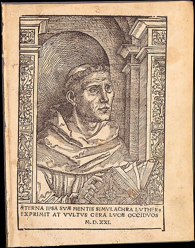 Martin Luther als Augustinermönch im Ordenshabit, Halbfigur nach rechts gewandt, mit Buch, vor einer halbrunden Nische, unter gestaffelten Rundbogen, mit Kämpfergesimsen und Ornamentpilastern