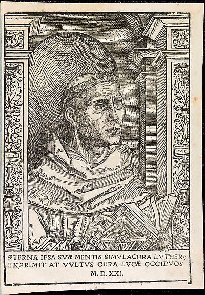 Martin Luther als Augustinermönch im Ordenshabit, Halbfigur nach rechts, mit Buch, vor einer halbrunden Nische, unter gestaffelten Bögen mit Kämpfergesimsen und Ornamentpilastern