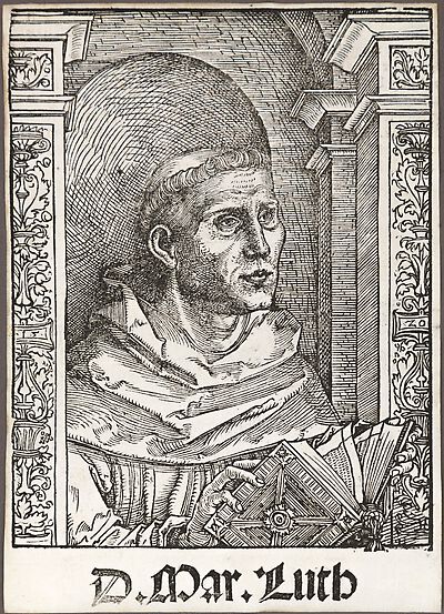 Martin Luther als Augustinermönch im Ordenshabit, Halbfigur nach rechts gewandt, mit Buch, vor einer halbrunden Nische, unter gestaffelten Rundbogen, mit Kämpfergesimsen und Ornamentpilastern